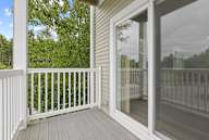 A white deck with a glass door and a white railing.