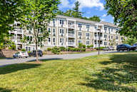 A large apartment building with a green lawn in front.