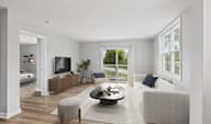A modern living room with a white couch, a coffee table, and a television.