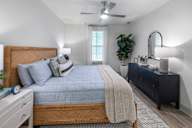 A bedroom with a bed, nightstand, and a plant.