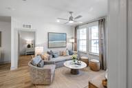 A modern living room with a grey couch, a coffee table, and a painting on the wall at Saltaire Apartment Homes in Santa Rosa Beach, FL