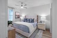 A bedroom with a bed, nightstand, and a ceiling fan at Saltaire Apartment Homes in Santa Rosa Beach, FL