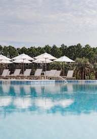 Lounge chairs and umbrellas at pool at Saltaire Apartment Homes in Santa Rosa Beach, FL