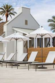 A white building with a patio and lounge chairs.