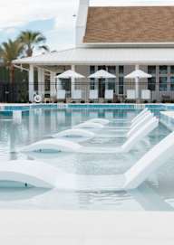 A pool with a white building in the background at Saltaire Apartment Homes in Santa Rosa Beach, FL