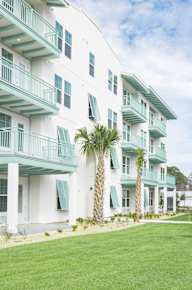 A white building with green trim and shutters at Saltaire Apartment Homes in Santa Rosa Beach, FL .