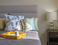 A bed with a yellow tray on it and a lamp on the nightstand at Dutch Village Apartments, Baltimore, MD