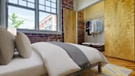A bedroom with a bed, pillows, and a striped blanket.