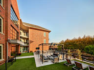 A modern outdoor seating area with a black metal pergola and wooden chairs.