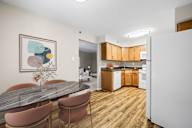 A kitchen with a table and chairs in the foreground and a refrigerator in the background.