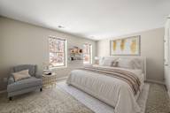 A bedroom with a bed, chair, and window.