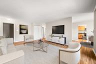 A modern living room with a white sofa, a coffee table, and a television.