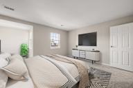 A bedroom with a bed, a television, and a window.