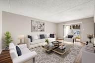 A living room with a white couch, a coffee table, and a large window.