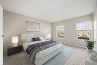 A bedroom with a large bed, two lamps, and a window.