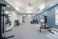 A spacious gym with a variety of equipment including treadmills, stationary bikes, and weight machines.