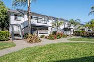 A modern apartment complex with a well-maintained lawn and landscaping.