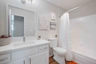A white bathroom with a toilet, sink, and mirror.