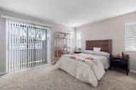 A bedroom with a large bed and a window with blinds.