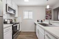 A kitchen with white cabinets and a black stove top oven.