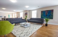 a living room with blue couches and green chairs