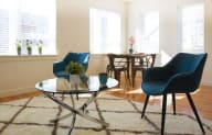 a living room with two blue chairs and a glass table
