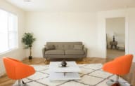 a living area with a couch coffee table and two orange chairs
