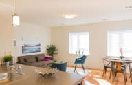 a living room with a couch a table and chairs and two windows