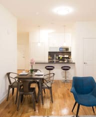 a dining area with a table and chairs and a kitchen in the background