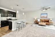 A modern kitchen with a bar area and a living room area with a couch.