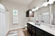A bathroom with a white sink and brown cabinets.