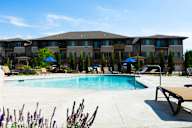 A pool area in front of a large apartment complex.