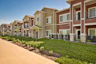A row of modern townhouses with well-maintained lawns and landscaping.