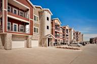 A row of modern apartment buildings with garages and cars parked in front.