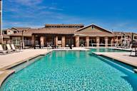 A large swimming pool in front of a building with a covered patio area.