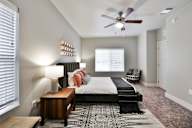 A bedroom with a bed, a nightstand, and a rug.