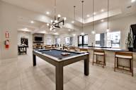 A billiard table is in the middle of a room with a fireplace and a bar area.