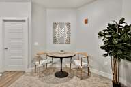 A white room with a round table and chairs and a plant.