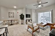 A living room with a ceiling fan and a flat screen TV.