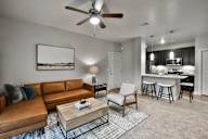 A living room with a brown leather couch, a coffee table, and a ceiling fan.