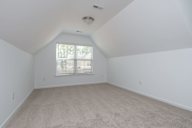 a spacious attic room with white walls and a window