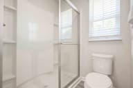 Modern bathroom featuring a glass shower enclosure and pristine white fixtures in a space-efficient design