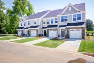 Elegant townhome facade with attached garages and well-maintained common areas in a serene setting