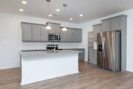 a kitchen with a large island and stainless steel refrigerator