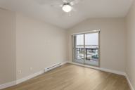 A room with a ceiling fan and a window overlooking a cityscape.