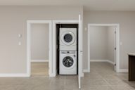A white dryer and washer are stacked on top of each other in a laundry room.