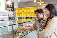 A man and woman are shopping for donuts in a bakery with a dog.