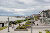 A group of people are walking on a sidewalk near a pier.