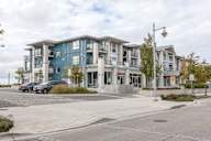 A modern apartment building with a parking lot in front.