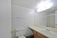 A white bathroom with a toilet, sink, mirror, and towel bar.
